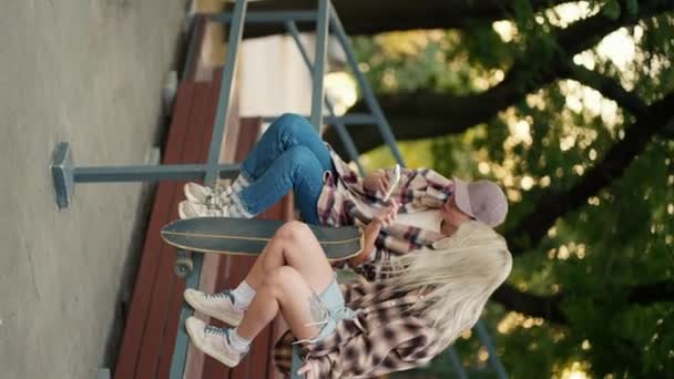 Vídeo Vertical Duas Meninas Camisas Xadrez Sentam Conversam Cerca Parque — Vídeo de Stock