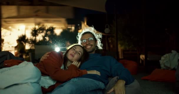 クローズアップショット 恋人のカップルは ビーンバッグの椅子に横たわり 映画を見ています 市外のパーティー カントリーハウスでの休憩 — ストック動画