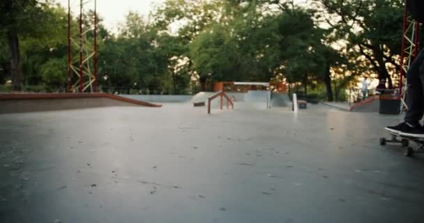 スケートパークに乗ったスケートボードの男のクローズアップショットと様々な障害を克服 夏のスケートパークで楽しいと極端なスポーツマン — ストック動画
