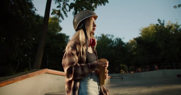 Een Blond Meisje Een Geruit Shirt Met Rode Hoofdtelefoon Drinkt — Stockvideo