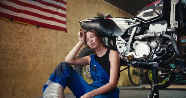 Tired Girl Auto Mechanic Black Top Blue Overalls Leans Motorcycle — Stock Video