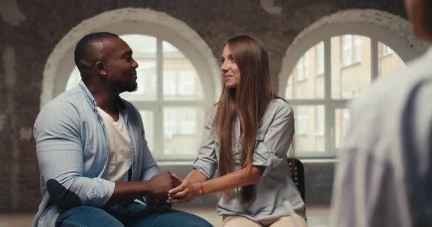 一对快乐的夫妇 一个穿着蓝色衬衫的黑皮肤的健康男人和一个金发女孩正在和一位心理学家谈话 在砖楼里与心理学家的私人谈话和治疗 — 图库视频影像