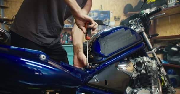 클로즈업 티셔츠 기계공 티셔츠를 남자는 작업장에서 스크류 드라이버가있는 파란색 오토바이를 — 비디오