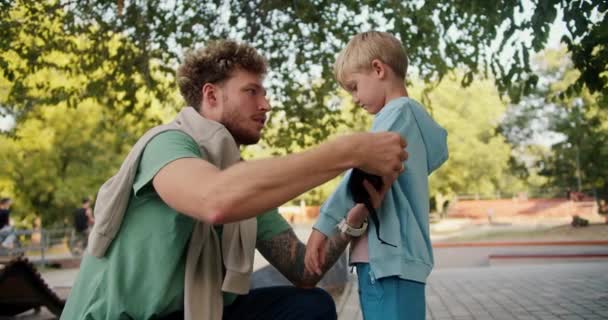 Muž Kudrnatými Vlasy Strništěm Zeleném Tričku Pomáhá Synovi Modrém Svetru — Stock video