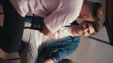 Dikey video: İki adam, mavi kot ceketli esmer bir adam ve pembe tişörtlü bir adam, grup terapisi sırasında iletişim kurup fikirlerini ifade ediyorlar..