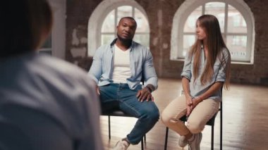 Mavi gömlekli fit bir adam ve grup terapisi sırasında uzun saçlı bir kız bir psikologla iletişim kuruyor..