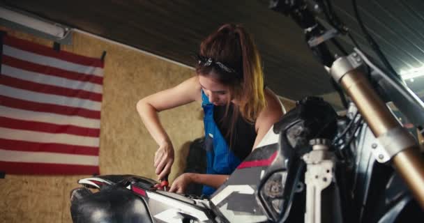 Крупным Планом Девушка Автомеханик Ремонтирует Мотоцикл Своей Мастерской Отверткой Фоне — стоковое видео
