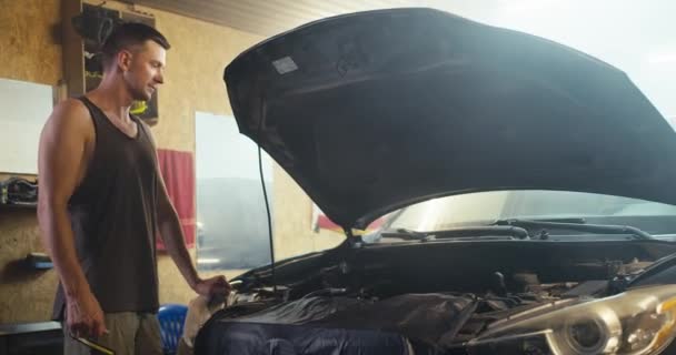Ein Mann Mit Kurzhaarschnitt Und Grauem Shirt Inspiziert Die Motorhaube — Stockvideo