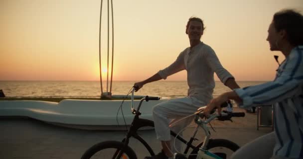 Kille Ljusa Sommarkläder Och Tjej Randig Skjorta Cyklar Längs Havet — Stockvideo