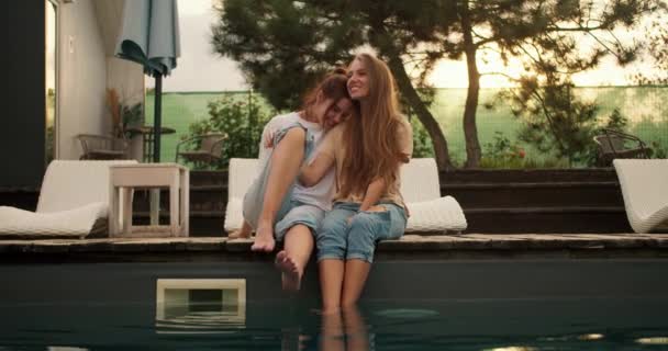 Duas Namoradas Estão Sentadas Perto Das Espreguiçadeiras Junto Piscina Abraçando — Vídeo de Stock