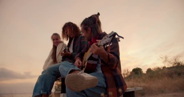 Два Парня Сидят Играют Гитаре Две Девушки Слушают Своих Парней — стоковое видео