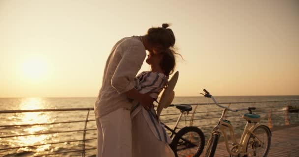 남자와 셔츠를 여자는 여름에 일출에 그들의 자전거 보드와 해변에서 — 비디오