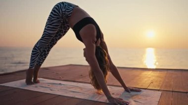 Siyah bluzlu, siyah beyaz pantolonlu genç bir kız yoga yaparken ve Kobra pozu verirken spor yaparken spor yaparken spor yapıyor.