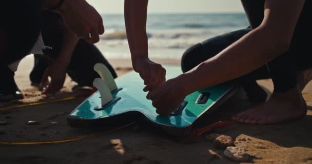两名男子在夏末的沙滩上与朋友一起在海滩上竖起鱼翅和冲浪板的特写镜头 — 图库视频影像