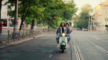 Kot ceketli mutlu bir adam, yaz aylarında şehir sokaklarında bir motosikletin farlarıyla motosiklet sürerken kollarını hareket ettiren ve dans eden kız arkadaşıyla gezer..