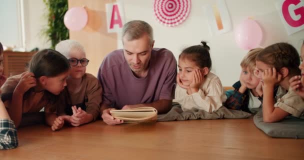 Man Gray Hair Purple Shirt Teacher Reads Book His Students — Stock Video