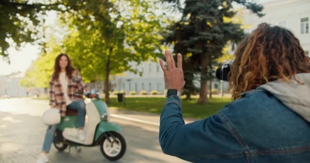 재킷에 머리를 남자는 오토바이에 앉아서 공원에서 올바르게 포즈하는 방법을 보여주는 — 비디오