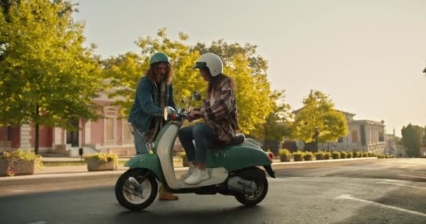 一个头发卷曲 头戴牛仔的男人在街上骑摩托车时帮助一个女孩移动 一个穿着格子衬衫的男人帮助他的女朋友骑摩托车 并在宽阔的街道上教她走路 — 图库视频影像