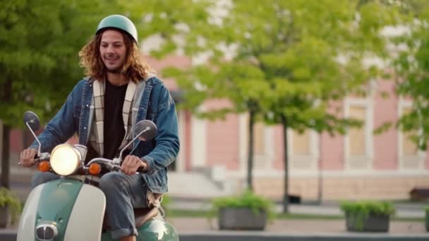 Ein Typ Mit Lockigem Haar Jeansjacke Und Grünem Mopedhelm Fährt — Stockvideo