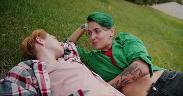 公園の芝生に明るいシャツを着た2人のレズビアン ガールズが デート中に互いに連絡を取り合う — ストック動画