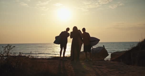 三个男人站在冲浪板上 在夏日的阳光下 他们在蓝色的大海边聊天 三个人站在海边看着太阳 手里拿着冲浪板说话 — 图库视频影像