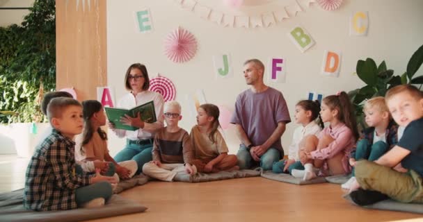 Блондинка Окулярах Зачіскою Боб Читає Зелену Книгу Дошкільного Віку Діти — стокове відео
