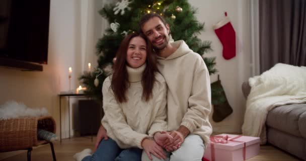 포옹과 겨울에 아늑한 크리스마스 집에서 카메라를 바닥에 스웨터에 남자와 여자의 — 비디오