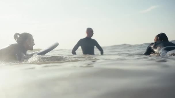 一个穿着湿衣的秃头男子站在海里 告诉他的朋友们如何正确地呆在冲浪板上 在海上训练冲浪者 — 图库视频影像