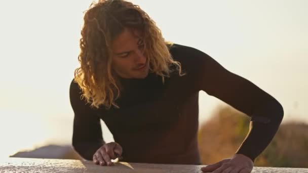 Cara Com Cabelo Encaracolado Wetsuit Sentado Processa Seu Surf Limpa — Vídeo de Stock
