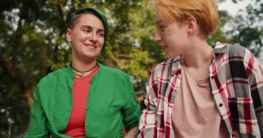 Yeşil tişörtlü kısa yeşil saçlı bir kız ve kareli tişörtlü kısa saçlı sarışın bir kız parktaki randevularında konuşuyorlardı. Parkta buluşan iki lezbiyen..