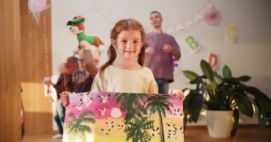 Portre: Güzel bir anaokulu kızı okul öncesi çocukların okula hazırlanması için bir kulübün teneffüs arkaplanına çizdiği resmini gösteriyor. Küçük kız anaokulu ressamı ona