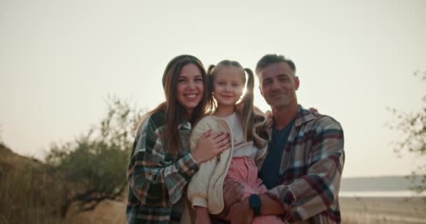 一个快乐家庭的画像 一个金发小女孩坐在她爸爸的怀里 一个头发灰白 穿着棕色格子衬衫的黑人男子 旁边是她的妈妈 一个穿着绿色衣服的黑人女孩 — 图库视频影像