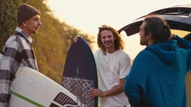 Trzech Szczęśliwych Facetów Trzymających Deski Surfingowe Dłoniach Rozmawiających Przy Samochodzie — Wideo stockowe