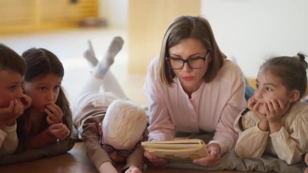 Zbliżenie Blondynki Okularach Różowej Koszuli Czytającej Dzieciom Książkę Klubie Przygotowującym — Wideo stockowe