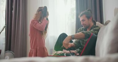 Pembe elbiseli esmer bir kız ve yeşil kareli gömlekli esmer bir adam olan babası, yolculuklarına başlamadan önce eşyalarını siyah bir valize koyup kapatıyorlar..