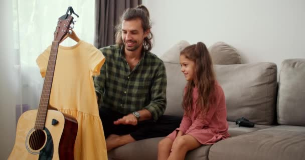 Mała Brunetka Różowej Sukience Siedzi Kanapie Obok Ojca Który Paruje — Wideo stockowe