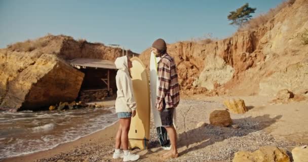 셔츠에 남자는 스웨트 셔츠에 친구와 그녀를보고 그들은 해변에 서있는 자신의 — 비디오