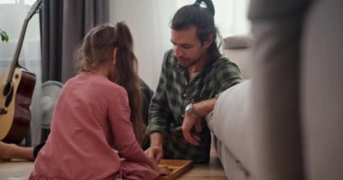 Pembe elbiseli küçük esmer bir kızın, babasıyla satranç oynadığını, yeşil tişörtlü esmer bir adamın, sonra da oyunu gri bir koltuğa yaslanmış özel bir kutuya koyduklarını düşünün.