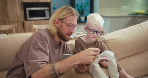 Menino Albino Feliz Óculos Azuis Senta Sofá Seu Pai Homem — Vídeo de Stock