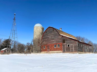 Bir tepenin ve taze kardan bir battaniyenin üzerinde terk edilmiş eski bir ahır oturuyor.