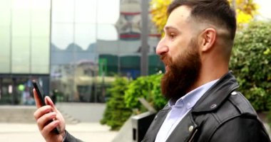 Yakın plan sakallı genç adam cep telefonu kullanarak sesli mesaj gönderiyor.. 