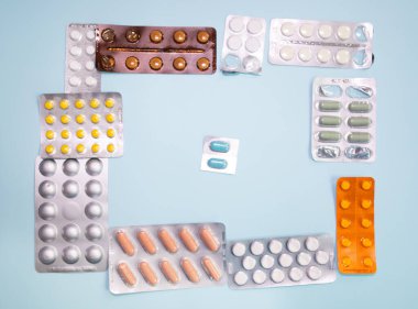 close-up view of scattered blister packs with different pills on blue background
