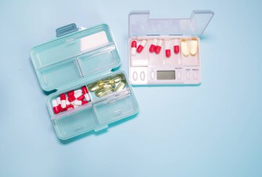 Plastic boxes with different pills on light blue background