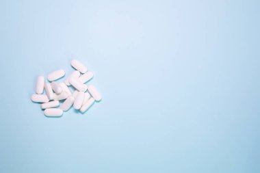 Spilled medications and pills on a blue background. Pharmacology and medicine struggle for health.