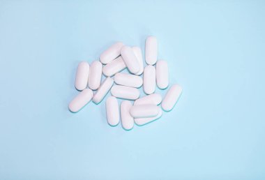 Spilled medications and pills on a blue background. Pharmacology and medicine struggle for health.