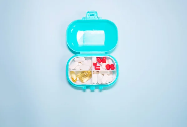 Caja Plástico Con Diferentes Píldoras Sobre Fondo Azul Claro —  Fotos de Stock