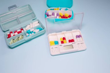 Plastic boxes with different pills on light blue background, top view. Space for text