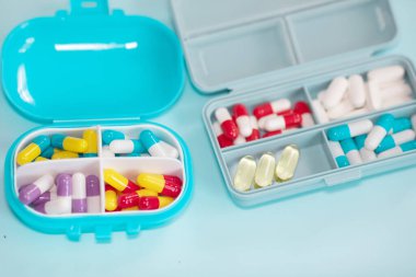 Plastic boxes with different pills on light blue background, top view. Space for text