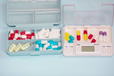 Plastic boxes with different pills on light blue background, top view. Space for text
