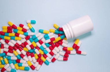 Medicine bottle and pills spilled on a light blue background. Medicines and prescription pills background 